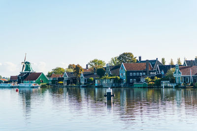 Buildings by river against clear sky