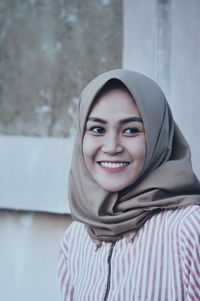 Woman wearing hijab while standing by wall