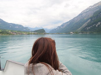 Rear view of woman looking at lake against mountains