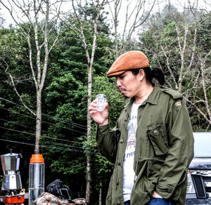 Man holding drink while standing at roadside