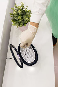 Hand in a protective glove puts the manicure scissors into the sterilizer