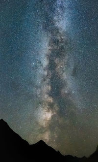 Low angle view of silhouette mountain against sky at night