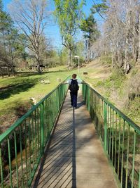 Rear view of woman walking on footbridge