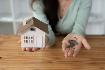 Midsection of woman holding model house