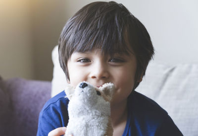 Portrait of cute boy holding stuffed toy at home