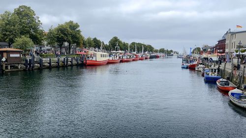 Boats moored in river against sky in city