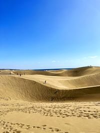 Scenic view of desert against clear blue sky