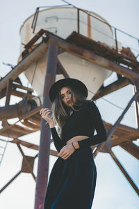 Woman standing by railing against sky