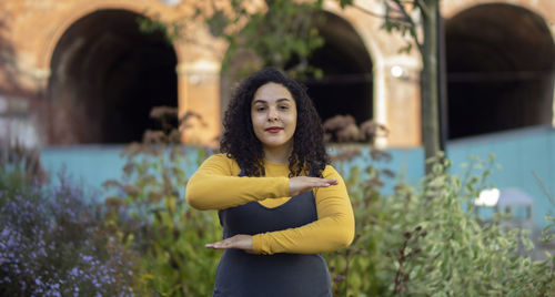 Portrait of woman gesturing while standing against plants