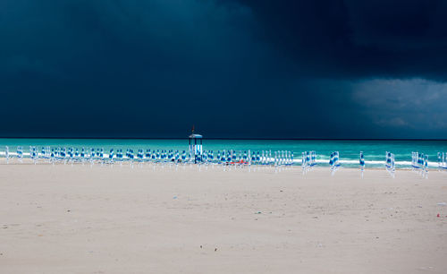 Beach umbrellas on beach against sky