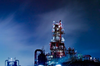 Low angle view of illuminated factory against sky at night