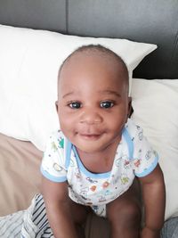 Portrait of cute baby girl on bed at home