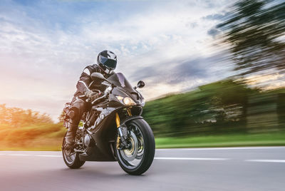 Man riding bicycle on road against sky