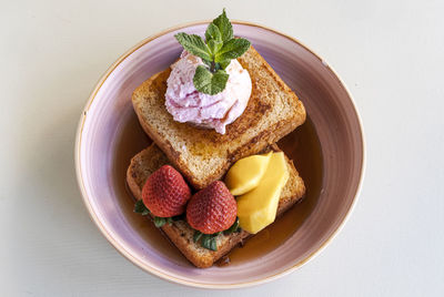 Toasts with strawberries, mango and ice cream with maple syrup in a bowl