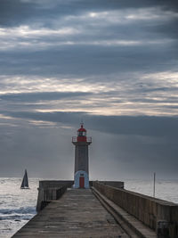 Lighthouse by sea against sky