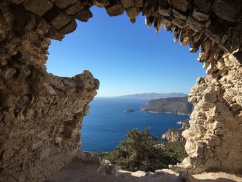 Rock formations by sea against clear blue sky