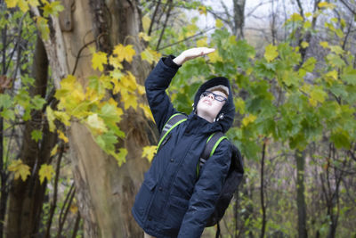 Boy shielding eyes while standing in forest
