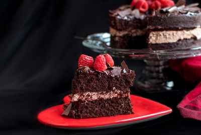 Decedent slice of chocolate cake topped with juicy red raspberries