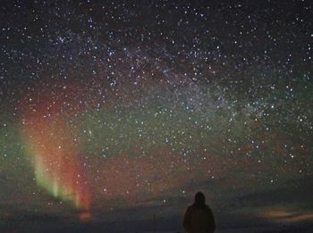 Rear view of silhouette man standing against star field at night