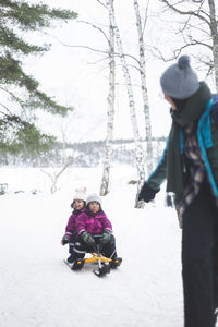 Girl and woman on snow covered trees during winter