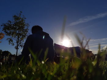 Rear view of man sitting on field against sky