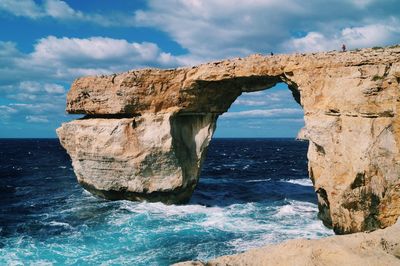 Scenic view of rock formation in sea against sky