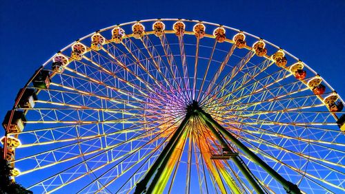 Low angle view of ferris wheel against blue sky