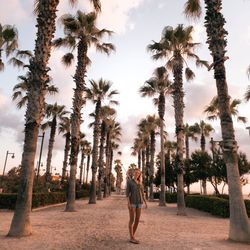 Full length portrait of woman standing on sand against trees