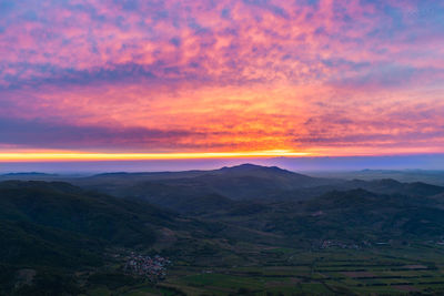 Scenic view of landscape against dramatic sky during sunset