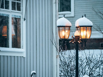 Close-up of illuminated lamp against building