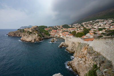 Aerial view of town by sea against sky