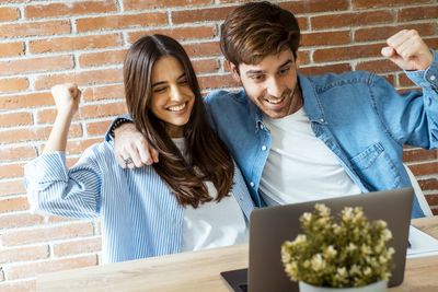 Portrait of smiling friends sitting on table