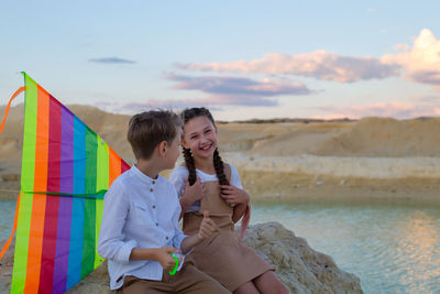 Teenage children watch the sunset lake in mountains.