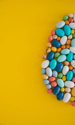 Easter candies are laid out in the shape of an egg on yellow background