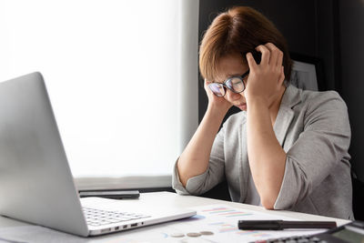 Tensed woman sitting by laptop on table in office