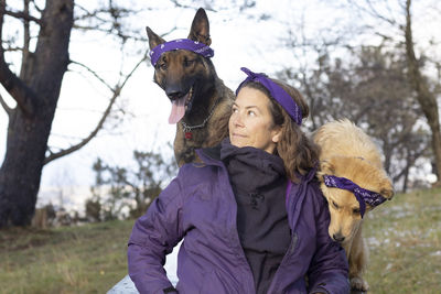 Blue eyed cinnamon dog, belgian shepherd malinois and brown haired girl with purple bandanas