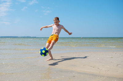 Full length of boy on beach against sky