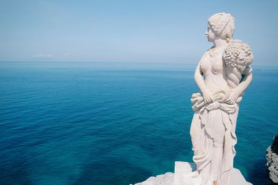 Statue by sea against sky