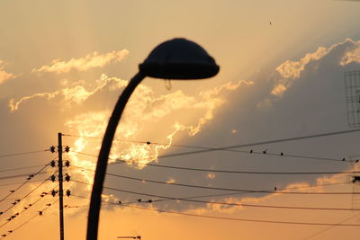 Low angle view of silhouette cables against sky during sunset