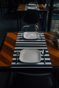 High angle view of empty plates with spoons and forks on table in restaurant