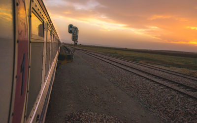 Train on railroad tracks against sky during sunset