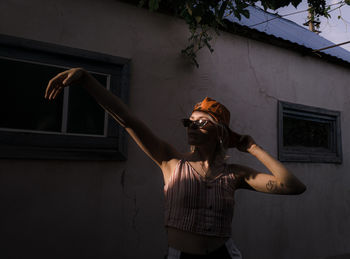 Young woman standing against building wall