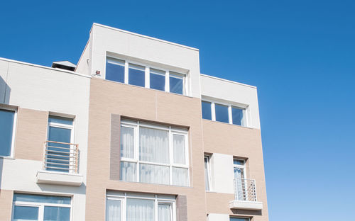 Low angle view of modern building against clear blue sky