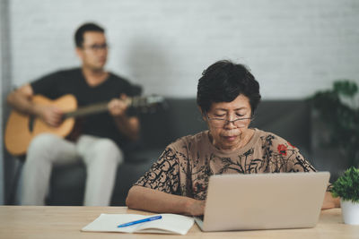 Young woman using laptop while sitting on table