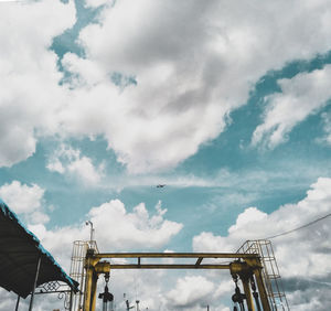 Low angle view of crane against cloudy sky