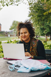 Smiling female student with laptop in college campus