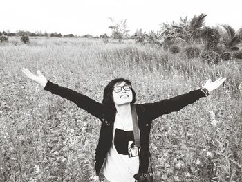 Full length portrait of young woman standing on field