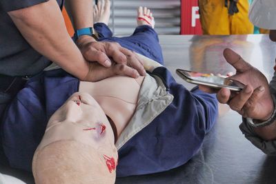Close-up of instructor teaching paramedic while performing cpr on dummy