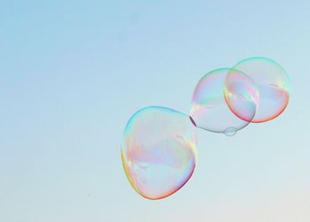 Low angle view of bubbles against rainbow over blue background