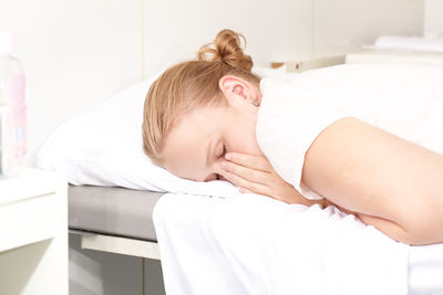 Young woman relaxing on bed at health spa